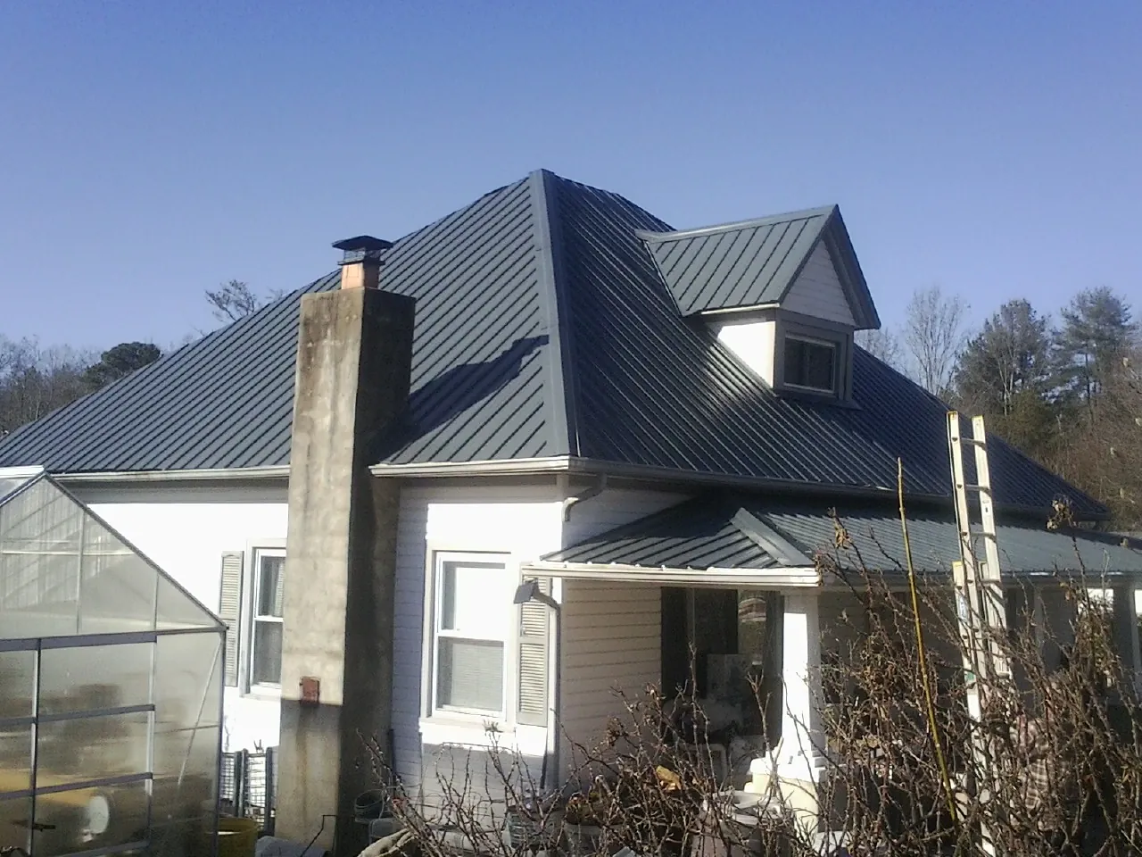 Dark blue standing seam metal roof on a white farmhouse with dormer — Slate & Tile Roof Repair by Roofing Brothers in New Gretna