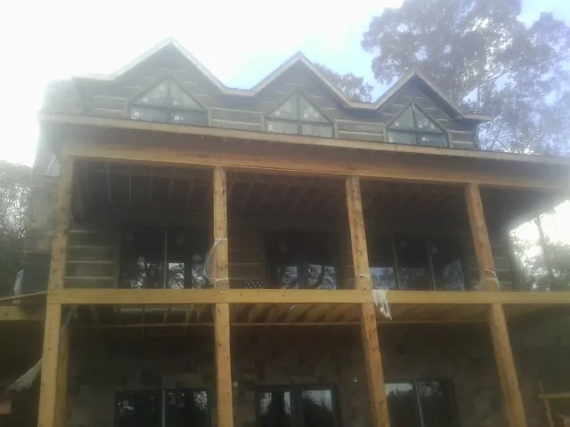 Dormers and porch framing on a large log home under construction — Roof Coating work by our crew in New Gretna