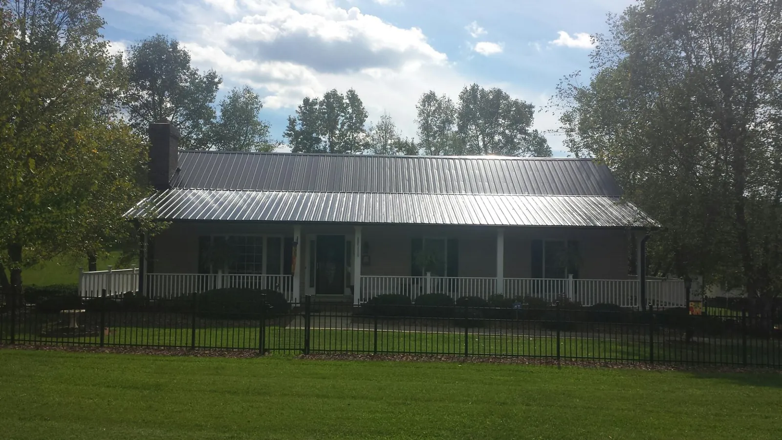 Gray metal roof on a brick ranch with a full width front porch — Gutter Guard Installation work by our crew in New Gretna