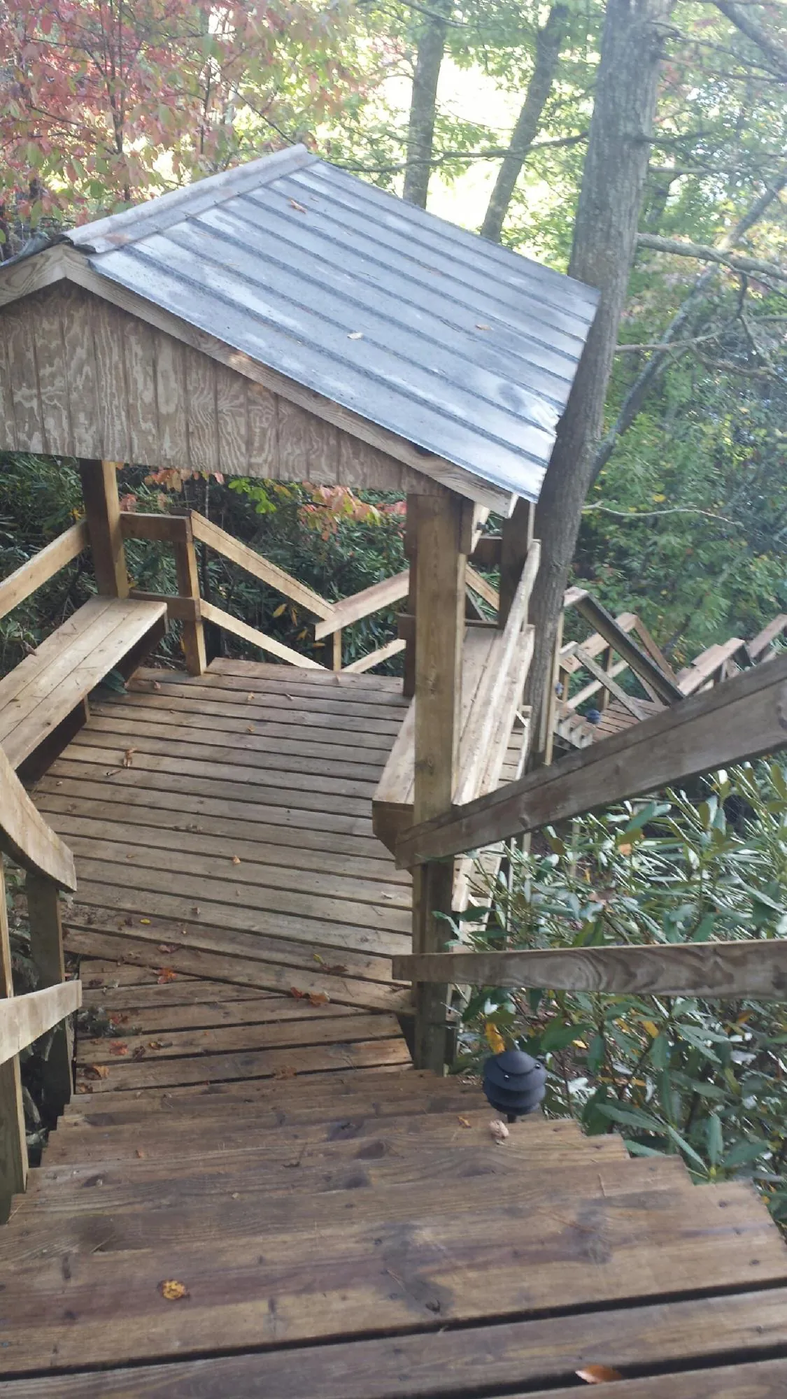 Metal roofed shelter over wooden steps on a wooded walkway — Skylight Repair & Installation work by our crew in New Gretna